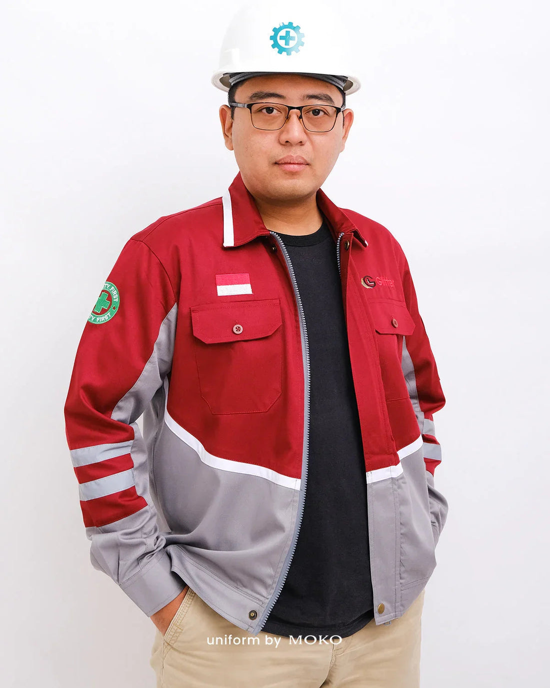 Man wearing maroon and gray uniform jacket with safety first patch and white hard hat